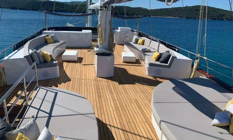 Lady Gita: Pont en teck avec canapés lounge blancs, coussins jaunes et bains de soleil face à la mer