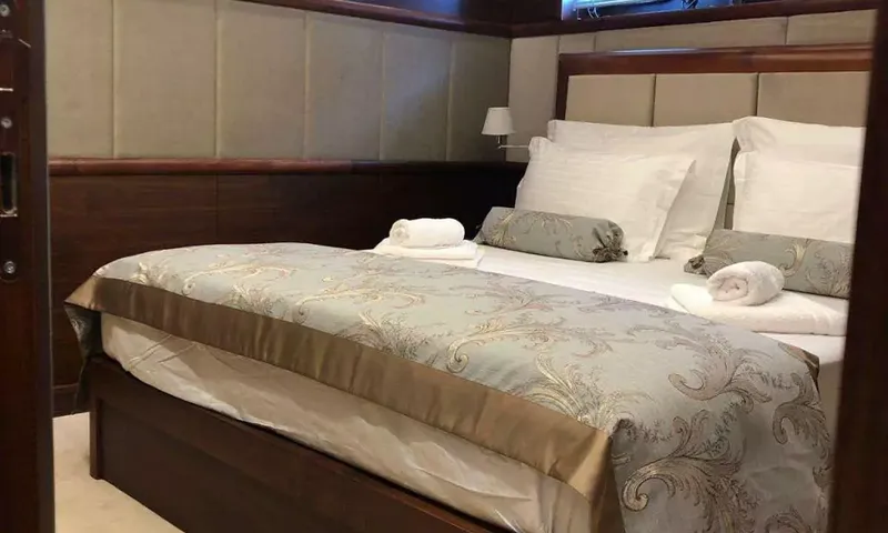 Lady Gita: Lit double avec plaid à motifs et serviettes roulées dans une cabine lambrissée de bois