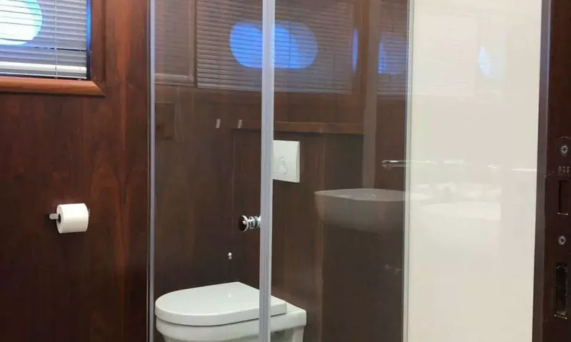 Lady Gita: Toilettes derrière une cloison vitrée dans un cabinet de toilette lambrissé de bois