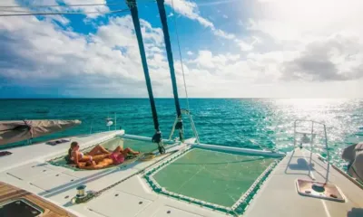 Lady Katlo: Two people sunbathing on the bow trampoline nets facing open sparkling sea