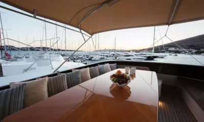 Lady Lona: Tavolo lucido del flybridge con ciotola di frutta e panca imbottita rivolta verso un porticciolo al tramonto