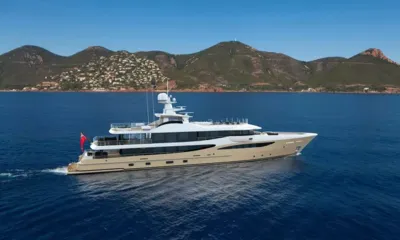 Lili: Yacht cruising on deep blue sea in front of green hills dotted with houses
