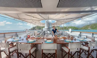 Maltese Falcon: Crew member setting a large round outdoor dining table under a canopy overlooking the bay
