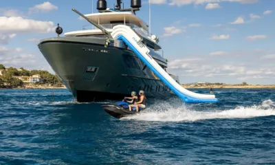 Moka: Two riders on a jet ski speeding past the yacht's bow with an inflatable slide from the deck