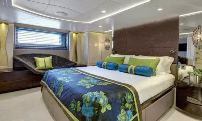 Mondango 3: Cabina con letto matrimoniale, plaid a fiori, cuscini blu e verdi, testiera imbottita e sedile accanto alla finestra