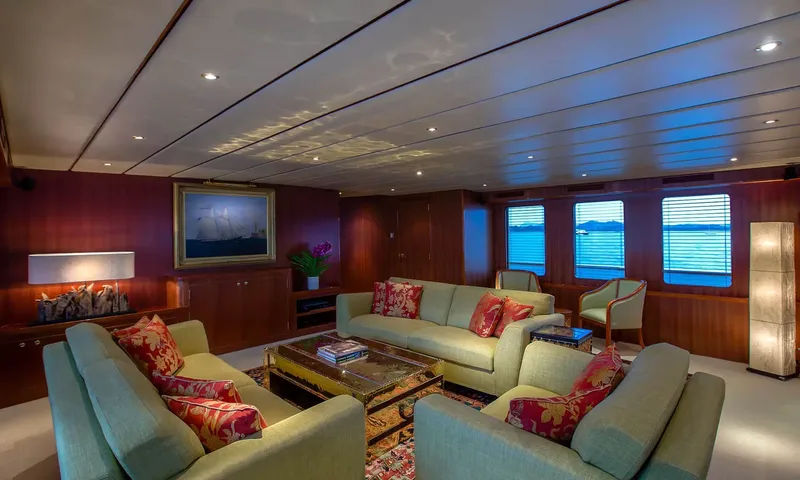 Northern Sun: Lounge with green sofas, red cushions, a gilded coffee table and a framed ship painting