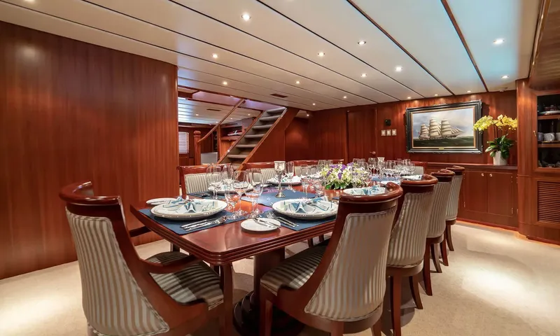 Northern Sun: Formal dining table set for many guests with striped chairs, flowers and a staircase behind