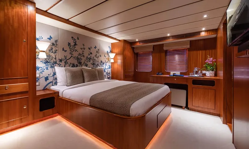 Northern Sun: Cabin with a double bed, blue floral wallpaper, wooden desk and shaded windows