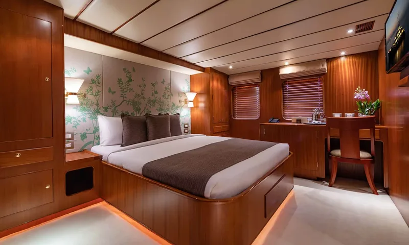 Northern Sun: Cabin with a double bed, green botanical wallpaper, a desk with chair and two windows