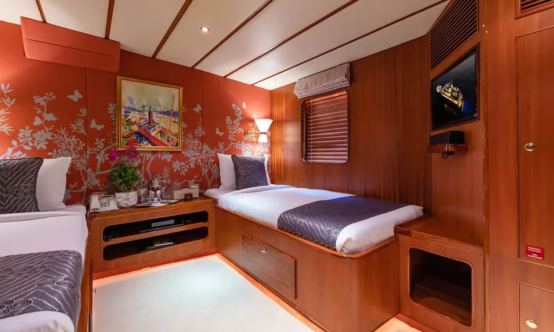 Northern Sun: Twin cabin with two single beds, orange floral wallpaper, a painting and a wall television