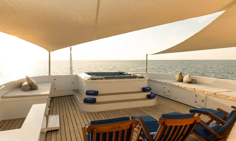 Northern Sun: Top deck with a raised hot tub, cushioned benches, deck chairs and shade sails over the sea