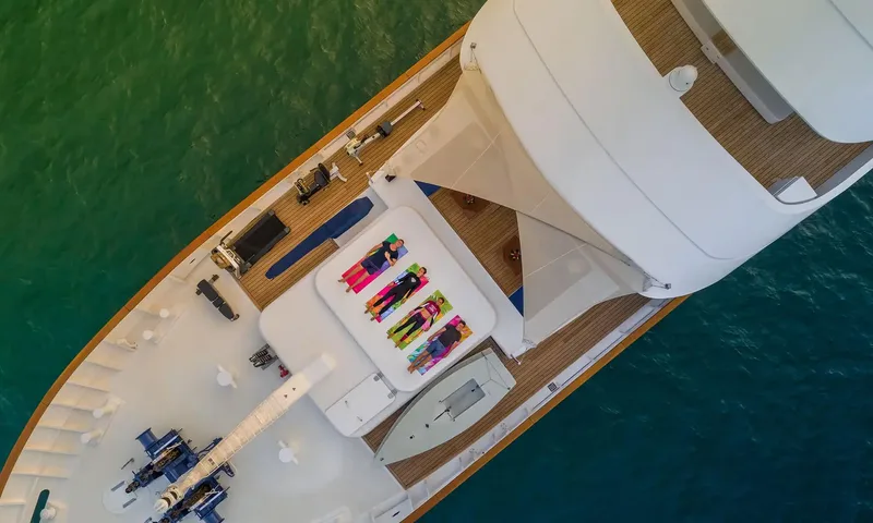 Northern Sun: Overhead view of the foredeck with people on yoga mats, exercise machines and a small boat