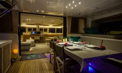 Ocean Views: Candlelit outdoor dining table set with glasses and flowers, open to the saloon