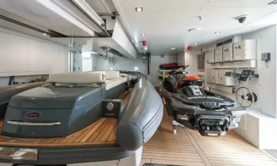 Petratara: Garagem do bote auxiliar com um bote auxiliar inflável cinza ao lado de um jet ski em piso de teca