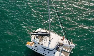 Polynesian: Overhead view of a catamaran on green sea with guests relaxing on the bow nets