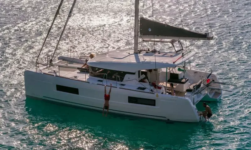 Grande: Catamaran at anchor on sparkling water as one guest dives off the side and another climbs aboard