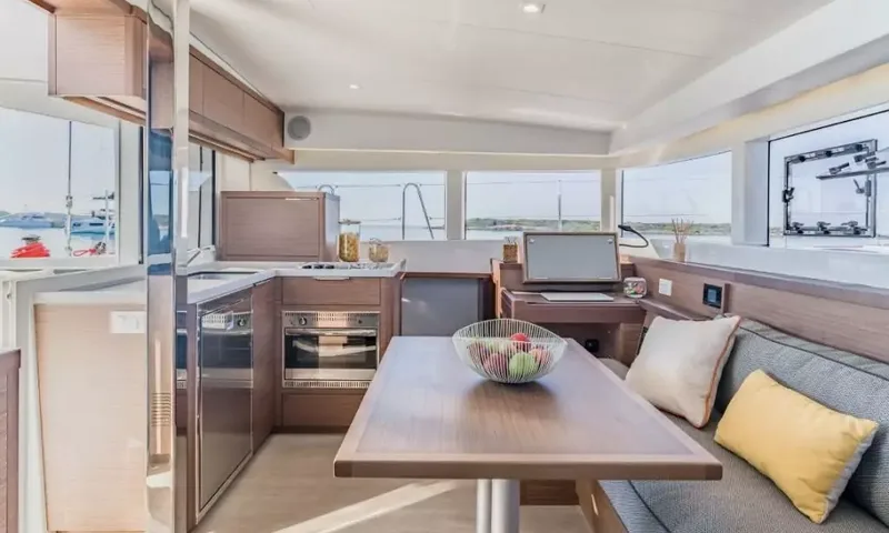 Grande: Saloon with dining table and sofa beside an open galley with oven and sink