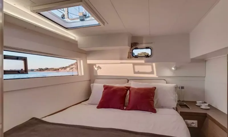 Grande: Double cabin with red cushions on the bed, hull window and overhead hatch