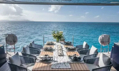 Relentless: Mesa de jantar de teca posta para oito no deck de popa, de frente para o mar aberto turquesa