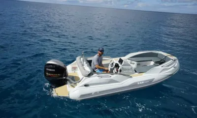 Relentless: Bote auxiliar inflável de casco rígido branco com motor de popa cruzando um mar azul profundo