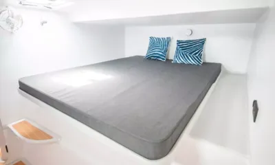 Sea Explorer: Cabine clara com cama de casal grande cinza e duas almofadas azuis estampadas
