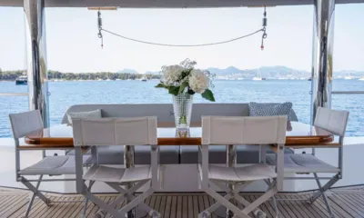 Seazen II: Mesa de jantar externa com cadeiras brancas e flores com vista para uma baía calma