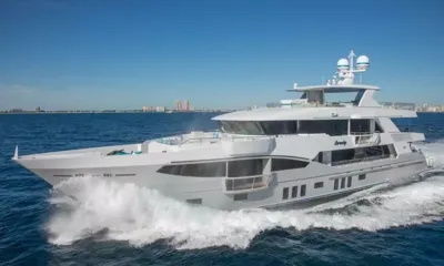Serenity: Yacht bianco in navigazione ad alta velocità sul mare blu con lo skyline della città dietro