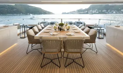 Seven Sins: Mesa de jantar externa posta com cadeiras trançadas com vista para uma baía ao anoitecer
