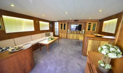 Simay F: Wood panelled lounge with long cream sofa, coffee table, television and grey carpet