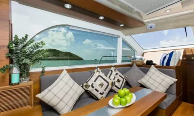 Splo1200: Salão com sofá cinza, almofadas estampadas, mesa de madeira com maçãs e janelas com vista para o mar