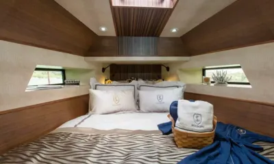 Splo1200: Cabine com cama de casal, painéis de madeira, janelas pequenas, toalhas e um roupão azul