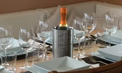 St Raphael: Gedeckter Tisch mit Gläsern und quadratischen Tellern um eine Flasche im Kühler