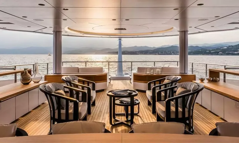 Suerte: Shaded aft deck with armchairs around a low table overlooking the sea at sunset