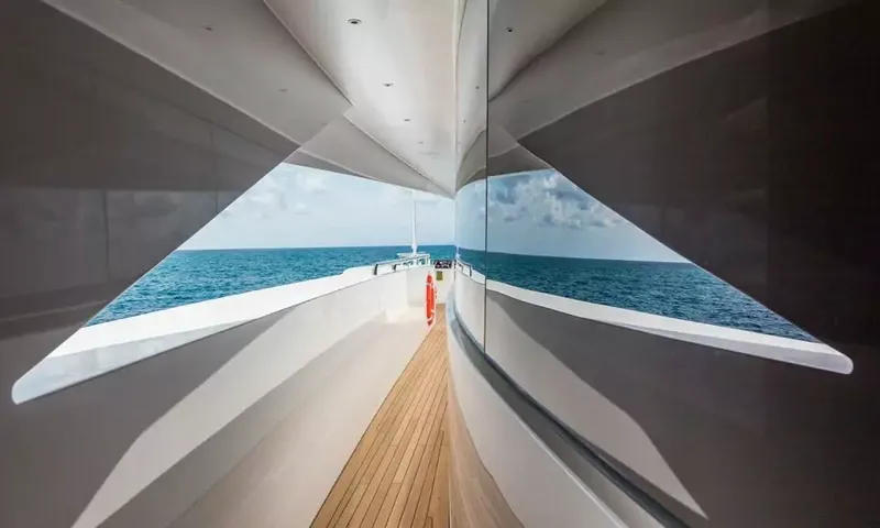 Suerte: Narrow teak side deck reflected in glossy panels with open sea ahead