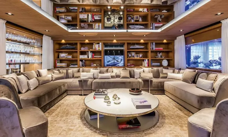 Suerte: Large U shaped velvet sofa around a round table with bookshelves and aquarium