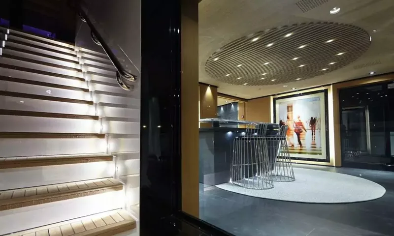 Suerte: Lit staircase beside a bar with wire stools and large artwork