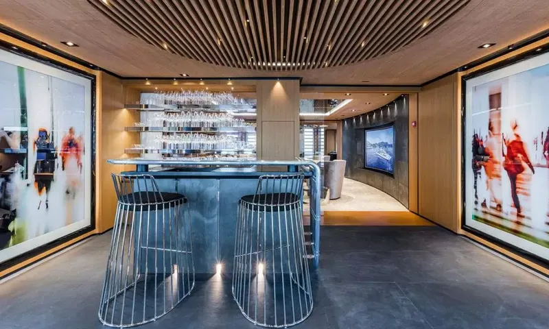 Suerte: Bar counter with two wire stools, glassware shelves and large paintings