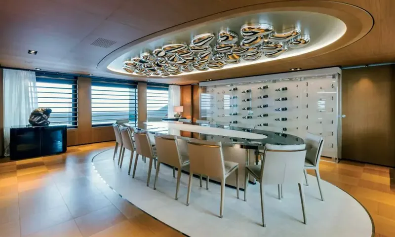 Suerte: Long oval dining table with white chairs below a sculptural ceiling light