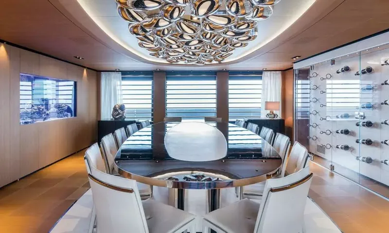 Suerte: Oval dining table with white chairs, wine display wall and aquarium