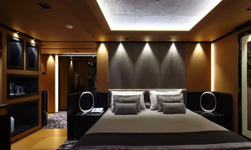 Suerte: Double bed with grey bedding and padded headboard in a warmly lit cabin