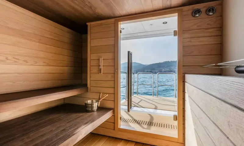 Suerte: Wooden sauna with benches and a glass door opening onto a deck and sea