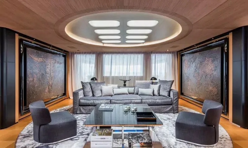 Suerte: Symmetrical lounge with grey sofa, two armchairs, glass coffee table and large textured wall art