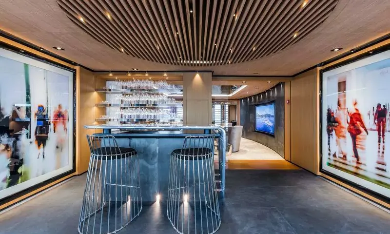 Suerte: Bar with two wire stools, glass shelves and large artworks leading to a lounge with screen