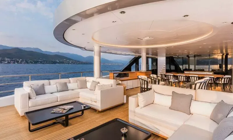 Suerte: Shaded aft deck with white sofas, coffee tables and dining area overlooking the sea and hills