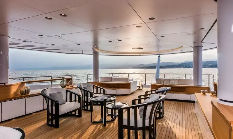 Suerte: Covered deck lounge with dark framed armchairs and side tables overlooking the sea