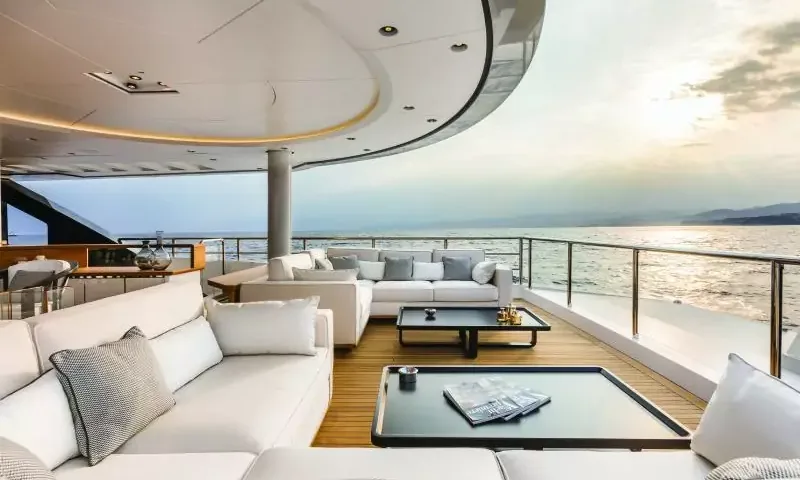 Suerte: Outdoor lounge with white sofas and low tables beside the railing at sunset