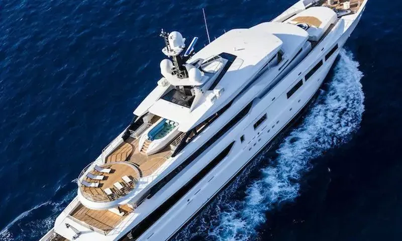 Suerte: White yacht cruising on deep blue sea seen from above, deck pool and sun loungers at stern