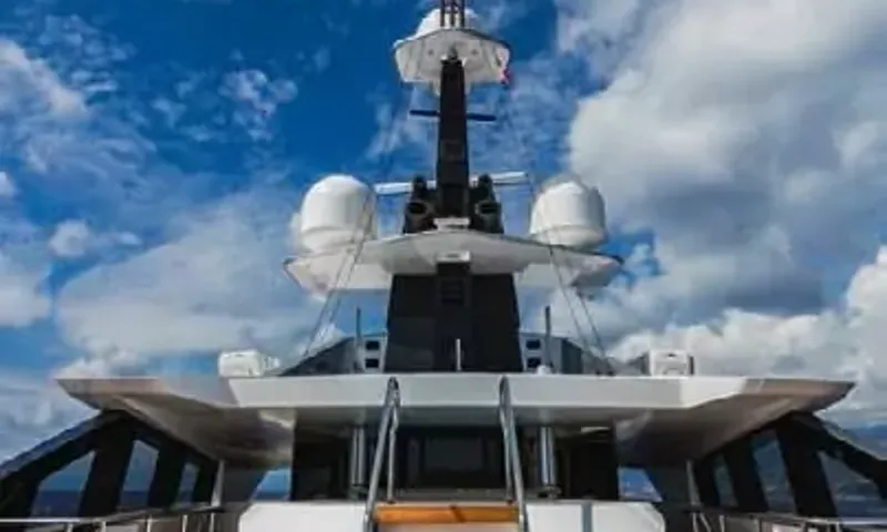 Suerte: Mast and radar domes above the upper deck against a cloudy blue sky