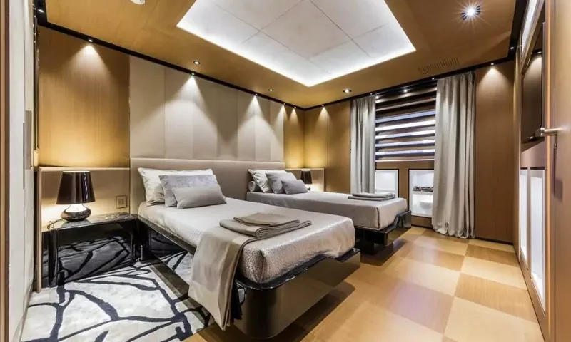 Suerte: Twin cabin with two single beds, bedside lamp, folded towels and wooden floor
