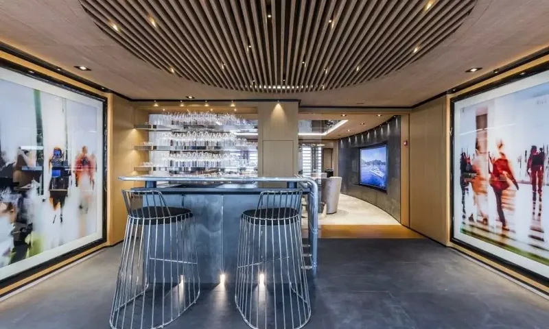 Suerte: Bar with two wire stools, glass shelves and large artworks leading to a lounge with screen